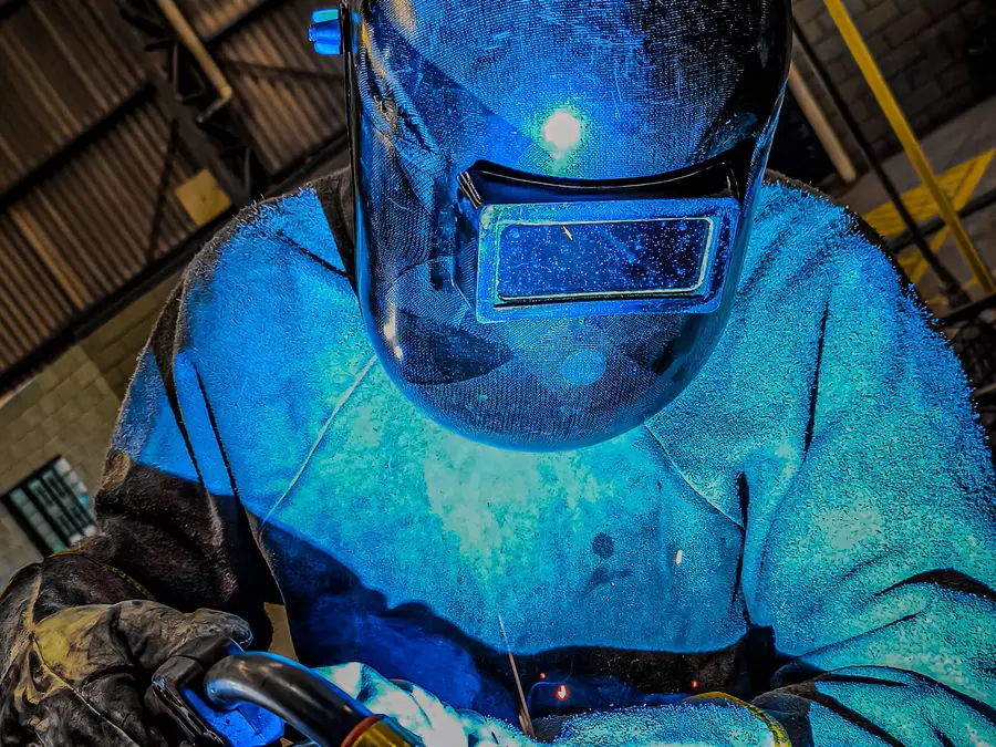 Soldador con equipo de protección completo trabajando en estructura metálica (imagen ilustrativa)